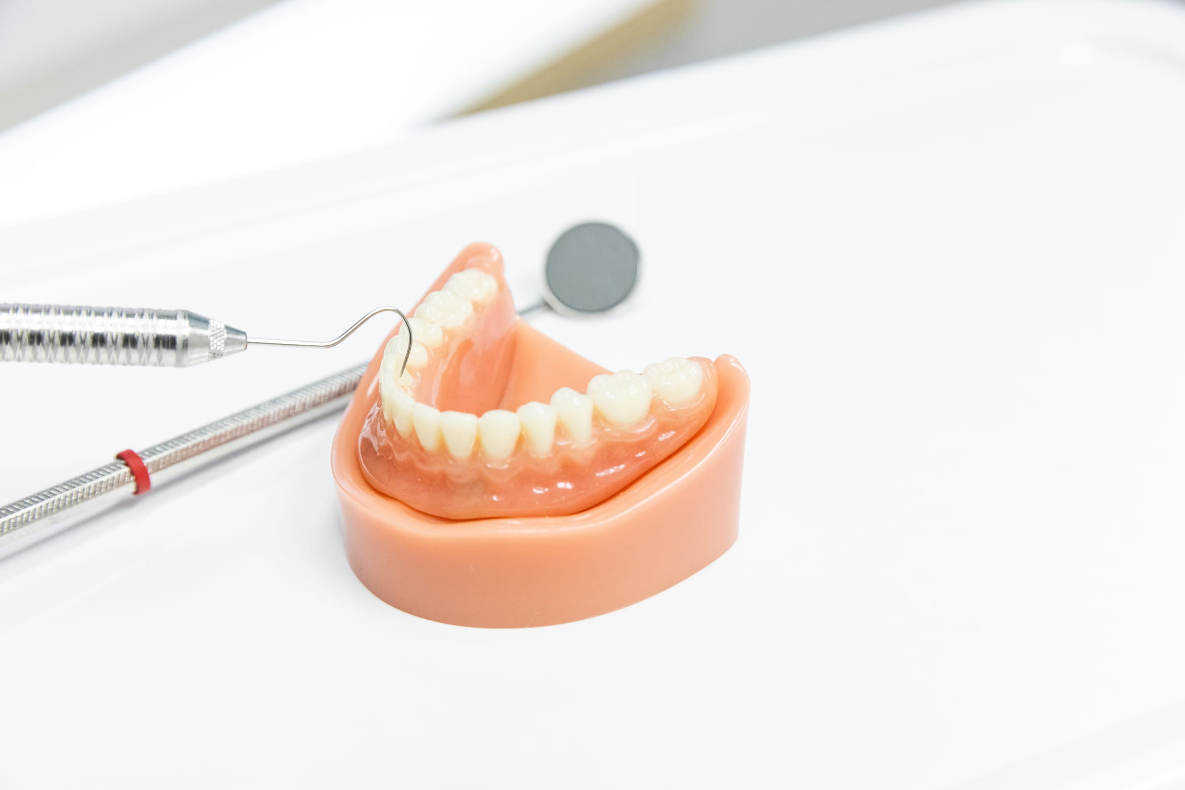 Une sonde parodontale posée sur un modèle de dents et de gencives