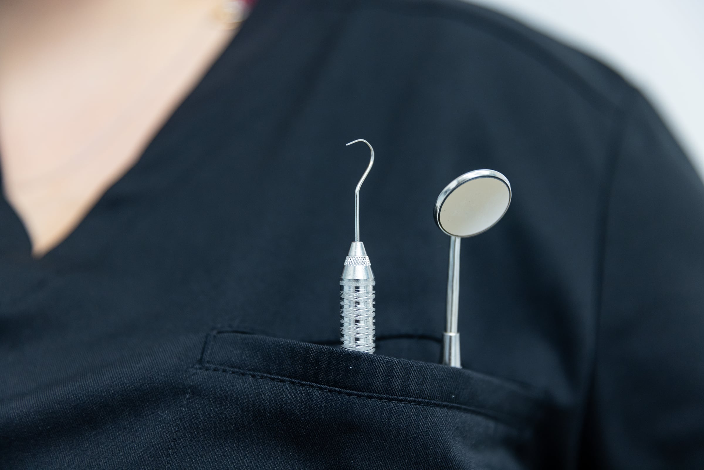 Un miroir et une sonde dentaires dans la poche d'un uniforme noir